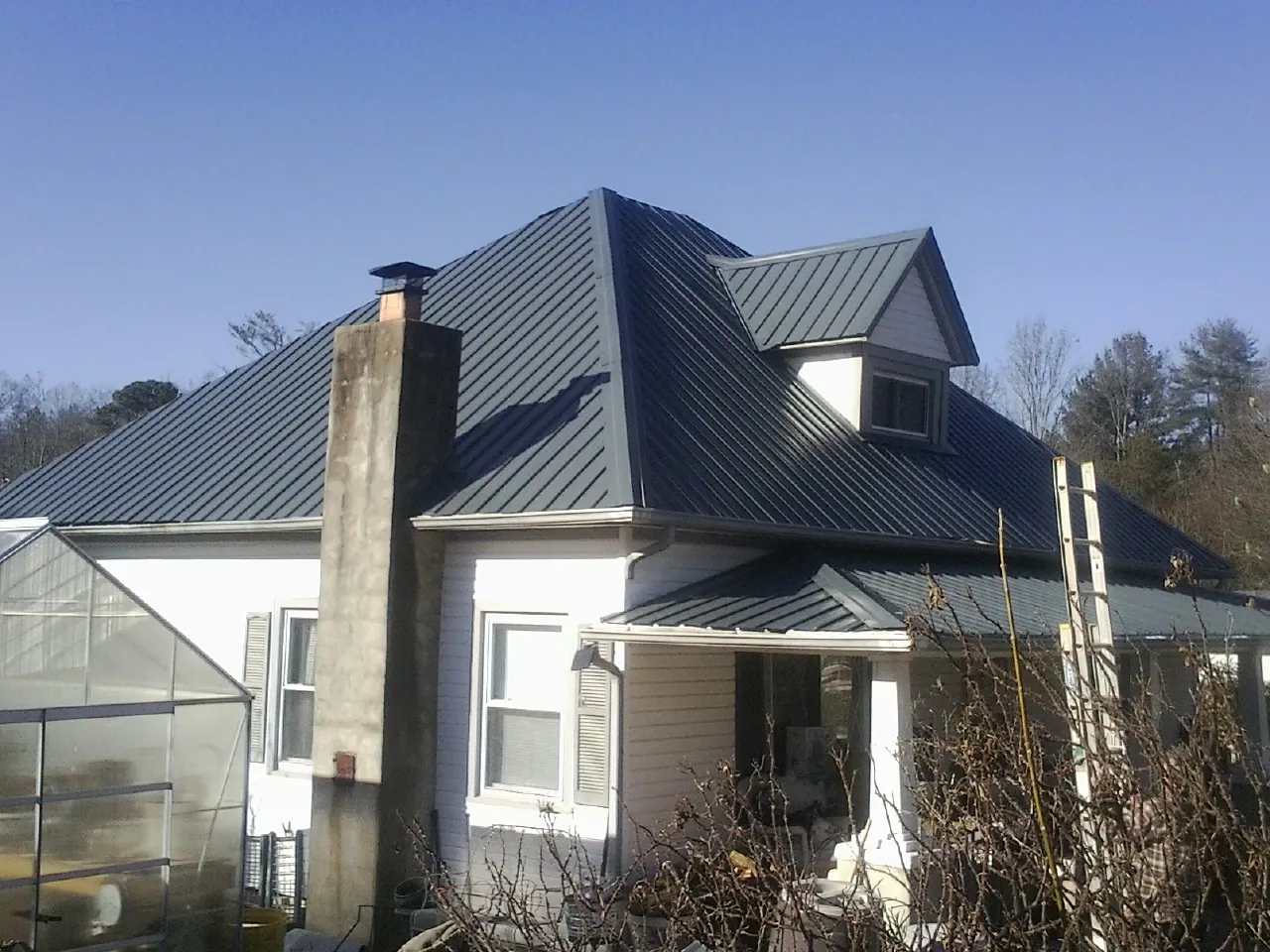 Dark blue standing seam metal roof on a white farmhouse with dormer — Slate & Tile Roof Repair by Roofing Brothers in Madisonburg