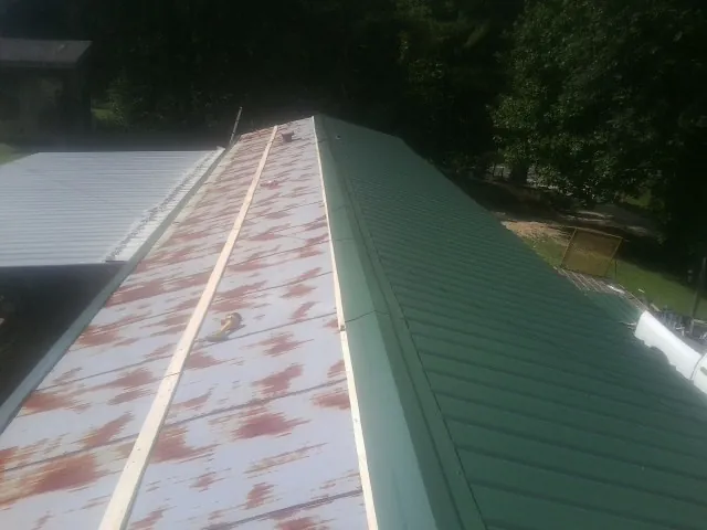 Old rusted panels beside newly installed green metal roofing — Wind Damage Roof Repair by Roofing Brothers in Madisonburg