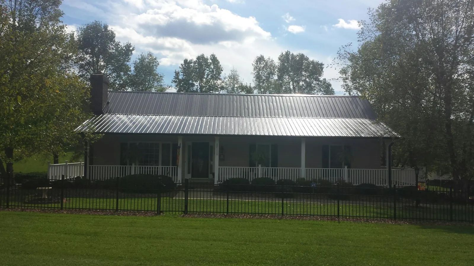 Gray metal roof on a brick ranch with a full width front porch — Gutter Guard Installation work by our crew in Madisonburg