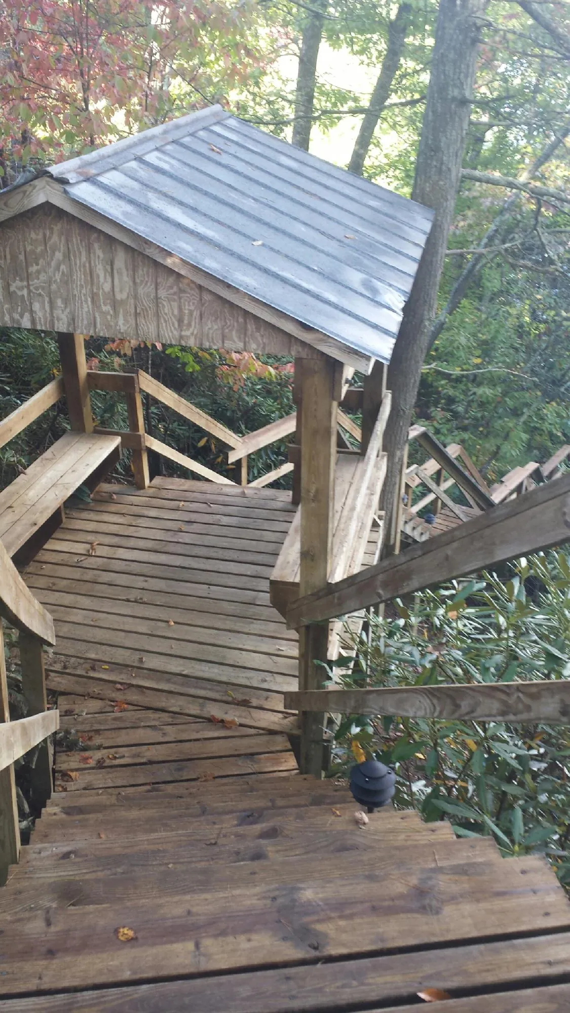 Metal roofed shelter over wooden steps on a wooded walkway — Skylight Repair & Installation work by our crew in Madisonburg