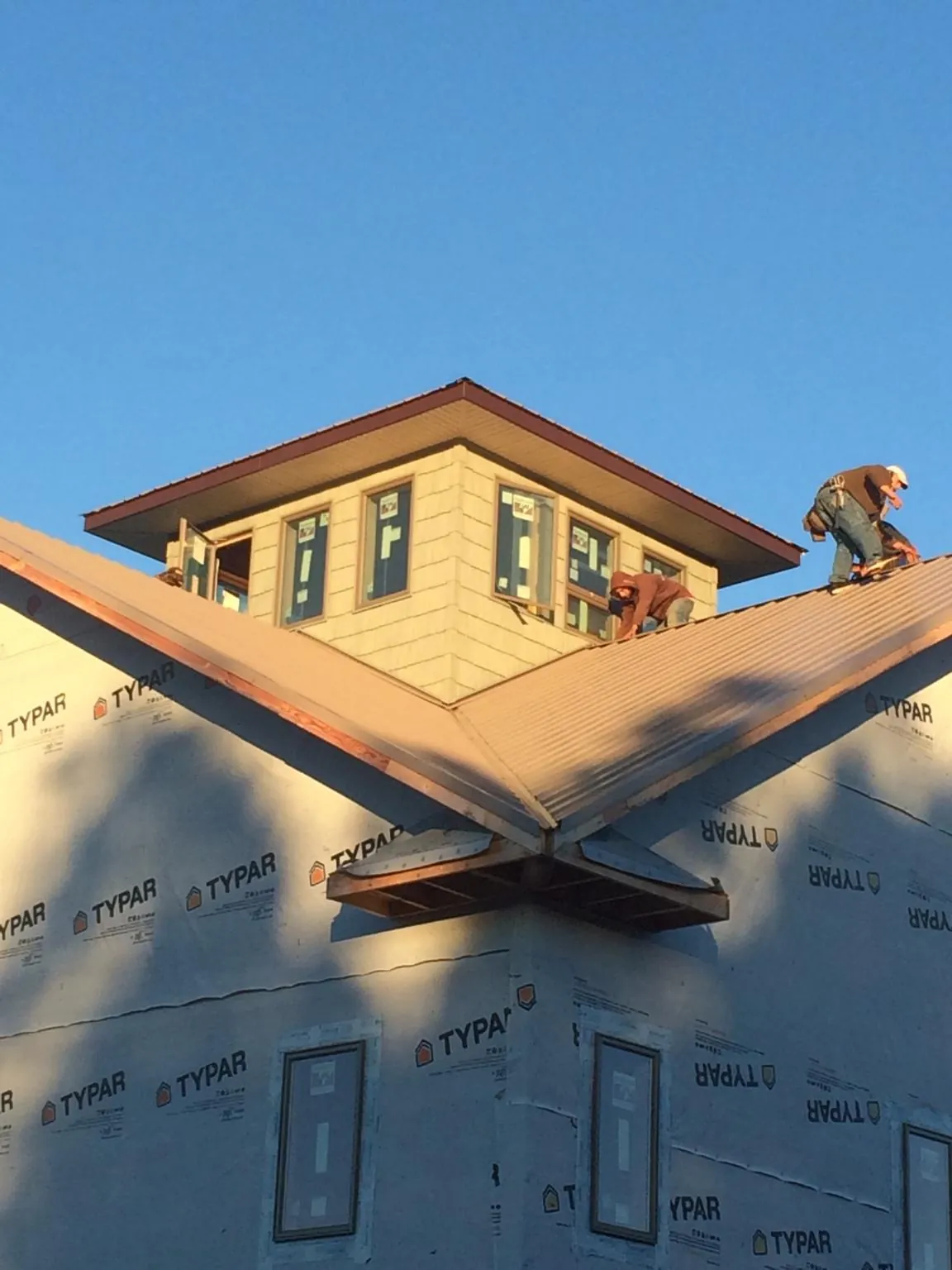 Roofers working around a rooftop cupola on a new metal roof at sunset — Roof Waterproofing in Madisonburg by Roofing Brothers
